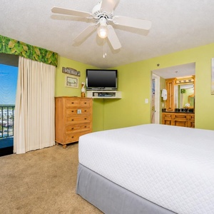 Master bedroom featuring a cozy king bed, a TV, and a scenic view through large sliding glass doors