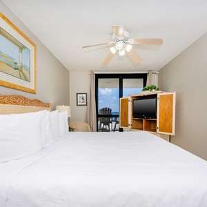 Master suite featuring a king bed, a TV unit, and access to a balcony with views of the beach