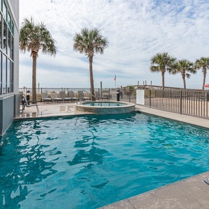 Relax by the beachfront pool and hot tub, surrounded by palm trees and inviting lounge chairs for a perfect getaway