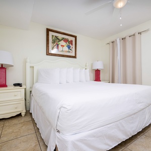 The master bedroom features a plush king bed, vibrant red lamps, and tasteful artwork, creating a relaxing atmosphere