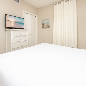 Relax in this inviting guest bedroom featuring a queen bed, a TV, and soft decor that enhances your restful experience