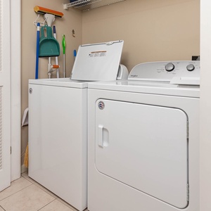 Laundry area featuring a washer and dryer with cleaning tools neatly organized on the wall for convenience during your stay