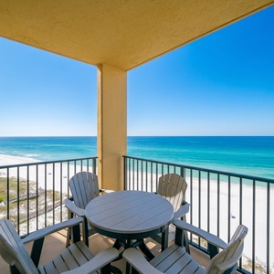Relax on the balcony with a round table and chairs, enjoying the serene view of the beach and gentle waves below