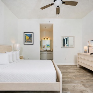 Guest bedroom featuring a cozy queen bed, modern decor, a flat-screen TV for relaxation, and balcony access