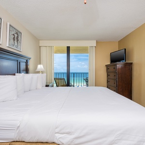Cozy master bedroom featuring a king bed and a breathtaking view of the beach from the balcony