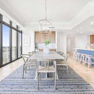 This bright dining area features a large table with eight chairs, and a view through expansive windows, perfect for gathering