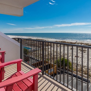 Enjoy a relaxing view from the balcony with red chairs overlooking the beachfront and sparkling waters