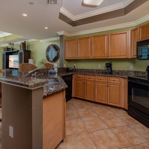 Prepare meals in this kitchen with elegant cabinetry, black appliances, and spacious countertops