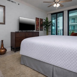Relaxing master bedroom featuring a king bed, modern TV, and balcony access for a relaxing experience