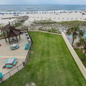 Enjoy the serene beach view from your balcony, overlooking the inviting pool and lush green lawn