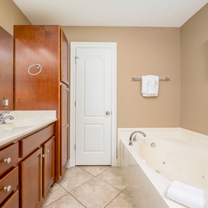 The master bath features elegant wood cabinetry, a relaxing jetted tub, and fresh towels for a rejuvenating experience