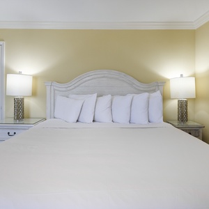 Brightly lit master bedroom featuring a large king bed adorned with plush white pillows and stylish bedside lamps