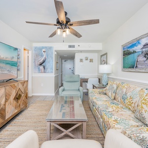 The living area features a colorful sofa with queen sleeper, and a large TV, creating a relaxed and inviting atmosphere