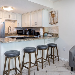 Modern kitchen with granite countertops, stainless appliances, and cozy seating at the stylish bar