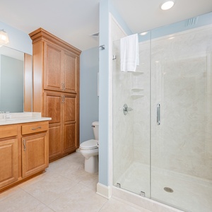 Enjoy a relaxing shower after a day at the beach in this guest bath with stylish cabinetry and spacious vanity