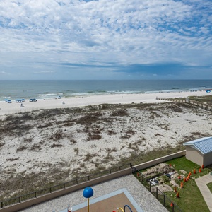 Relax at the outdoor splash park area, with a view of the beach and inviting lounge chairs under colorful umbrellas
