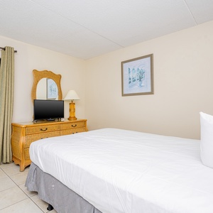 This wecoming bedroom features a comfortable bed, a stylish dresser, and a lovely view of the surrounding area