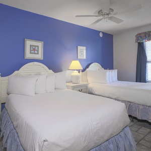 Brightly colored walls complement two double beds, creating a cheerful atmosphere in this inviting guest bedroom