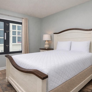 Inviting guest room with a cozy queen bed, stylish lamps, and large windows for natural light