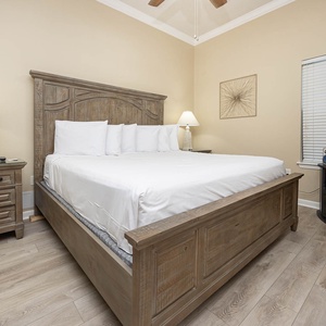 The bedroom features a king bed with crisp white linens, a stylish nightstand, and a mounted TV for entertainment