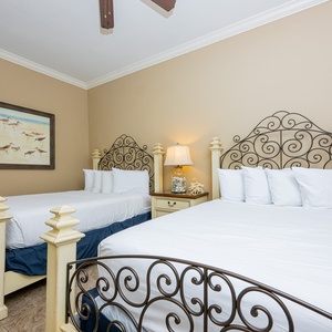 This guest bedroom features two elegant full beds with decorative iron headboards and a cozy lamp, perfect for restful nights