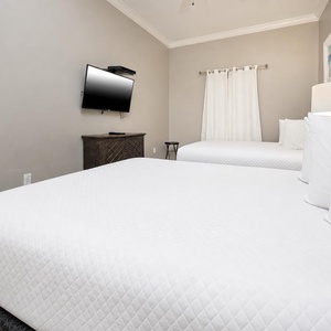 Relax in this guest room featuring two comfortable queen beds, a TV, and soft lighting for restful nights