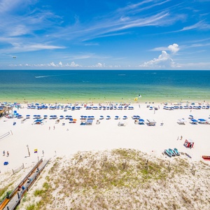 The stunning view showcases a vibrant beach scene with colorful umbrellas and soft white sand, perfect for relaxation and fun