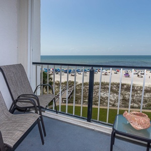 Enjoy a relaxing view from the balcony with two chairs overlooking the beach and colorful umbrellas on the sand
