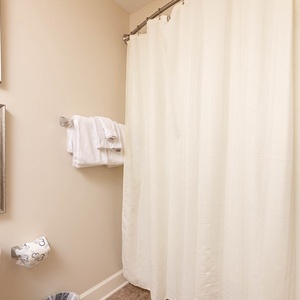 This bathroom features soft white towels, elegant wall art, and a shower curtain, creating a serene atmosphere for guests