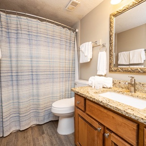 Guest bathroom featuring a granite countertop, a striped shower curtain, and fresh towels for a refreshing experience