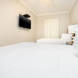 Relax in this guest bedroom featuring two comfortable queen beds, a large TV, and natural light