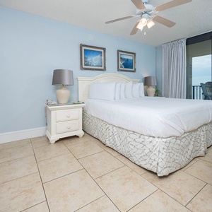 Serene master bedroom with soft blue walls, a comfortable king bed, and a beachfront view
