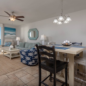 The inviting living area features a plush sofa with queen sleeper, a accent chair, and a dining table with coastal décor
