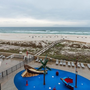 The view showcases a vibrant pool area with a pirate ship splash park and a serene beach just steps away
