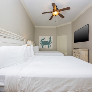 This guest bedroom features two comfortable full beds, a wall-mounted TV, and charming coastal decor for a relaxing stay