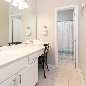 Master bathroom featuring a spacious vanity with a large mirror, fresh towels, and a shower curtain with subtle blue stripes