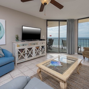 The inviting living area features a blue armchair, a stylish coffee table, and a large window showcasing the beach front