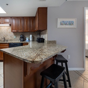 Warm wooden cabinetry complements the granite countertops in this inviting kitchen area, featuring a convenient breakfast bar