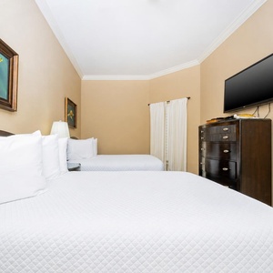 This cozy guest bedroom features two queen beds, a flat-screen TV, and charming turtle artwork on the walls