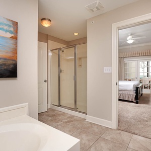 The master bath features a relaxing jetted tub, a walk-in shower, and a view into a cozy bedroom with soft, neutral tones