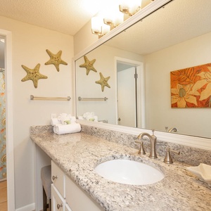 Vibrant master bathroom featuring a spacious countertop, decorative starfish accents, and a soothing tub/shower combo