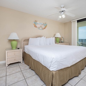 Master suite bedroom features a king bed, tropical accents, and sliding glass doors leading to the extended beach balcony