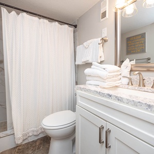 This bathroom features a stylish design, spacious shower, elegant fixtures, and neatly arranged towels for your convenience
