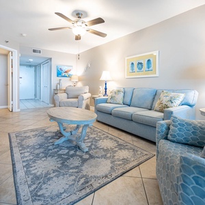 The living area features a light blue sofa with queen sleeper, armchair, and coffee table, creating a relaxed beach vibe