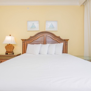 Inviting guest bedroom featuring a queen bed, warm yellow walls, and charming nautical artwork