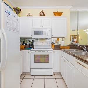 White cabinetry surrounds the stove and microwave in the kitchen where you prepare vacation meals with ease