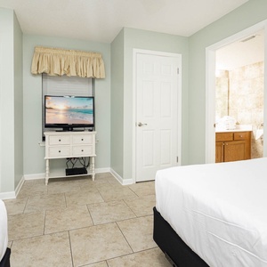 Inviting guest room featuring two beds, a queen and a double, a TV, and easy access to the adjoining guest bath
