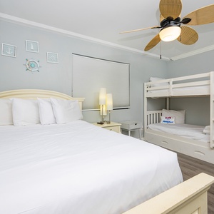 This guest bedroom features a queen bed and a bunk bed, perfect for family stays, with nautical decor enhancing the ambiance