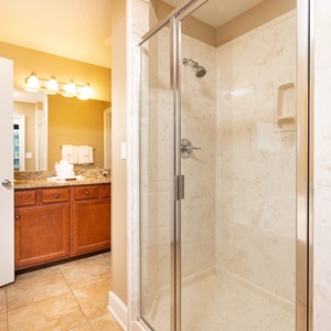 The master bath features a stylish glass walk-in shower, elegant granite countertops, and warm lighting for a relaxing stay