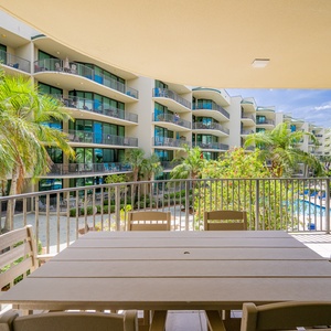Savor the coastal breeze on your inviting balcony, surrounded by lush greenery and poolside tranquility